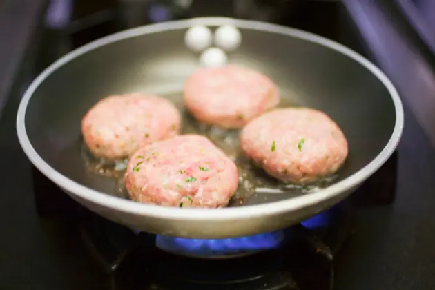Frozen burger patty cooking in a skillet
