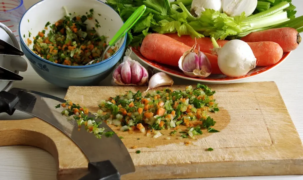 Finely chopped onions, celery, and carrots on cutting board