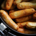 a bunch of sausages in an air fryer basket