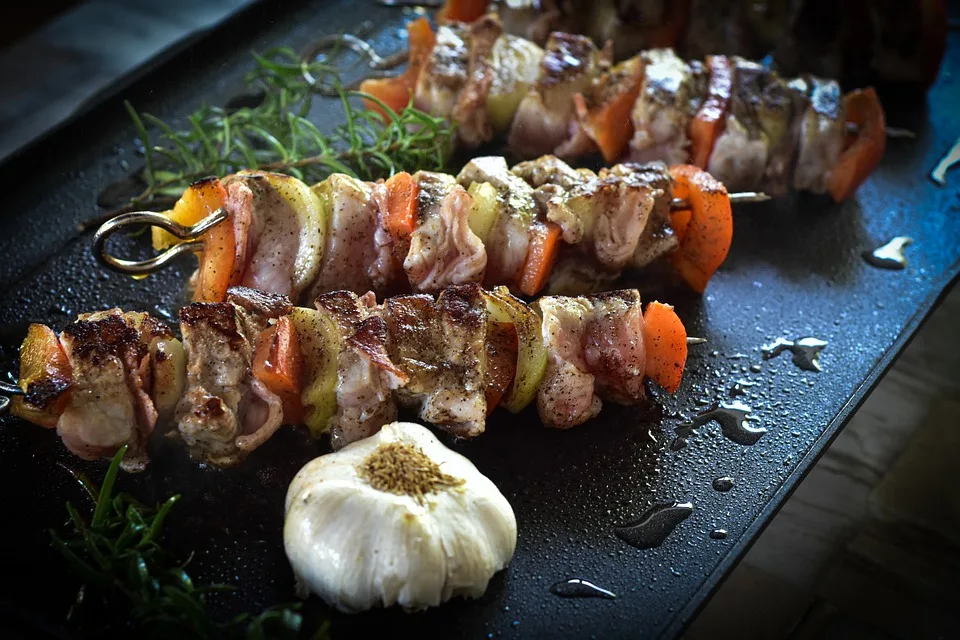 meat skewers aside some garlic and rosemary, ready to be served with ravioli