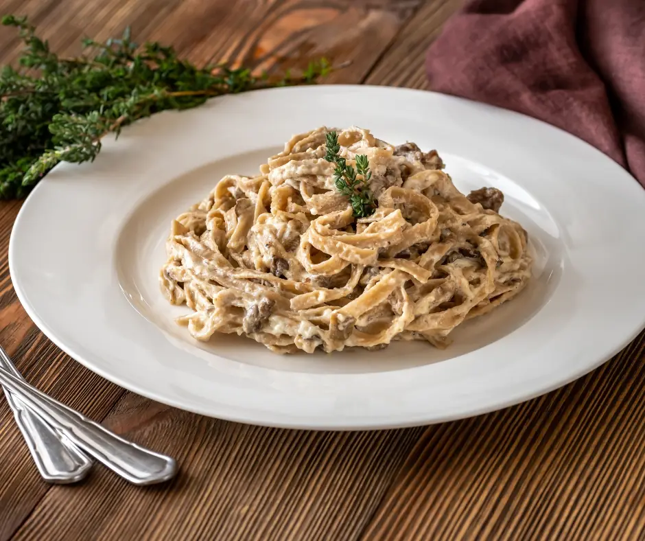 a plate full of tagliatelle with bechamel sauce and mushrooms