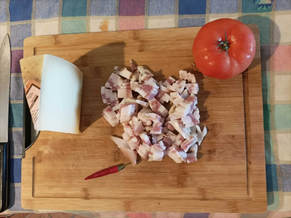 some of the ingredients for amatriciana pasta on a wooden surface