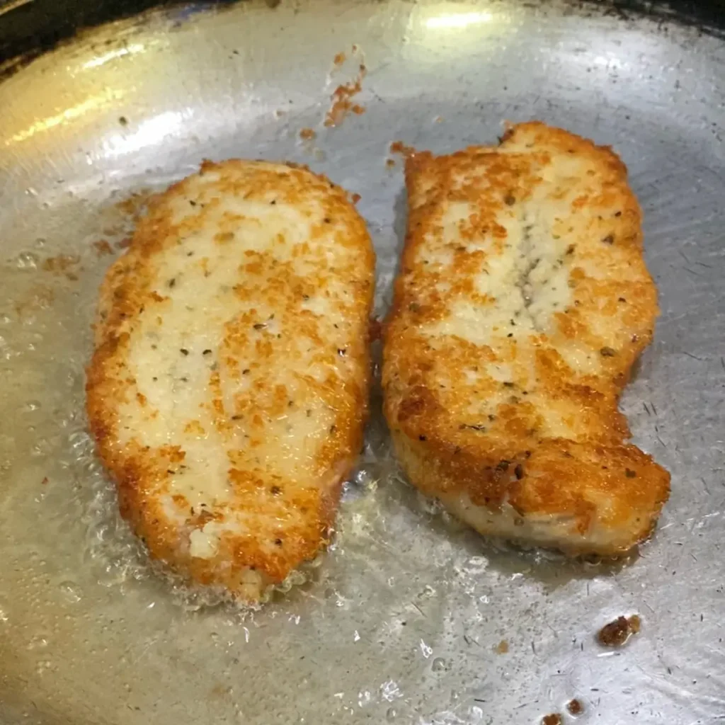 milanesa recipe-2 slices of chicken milanesa with no flour or breadcrumbs frying in a saucepan