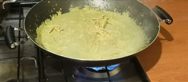 detail of bucatini cooking in pesto sauce
