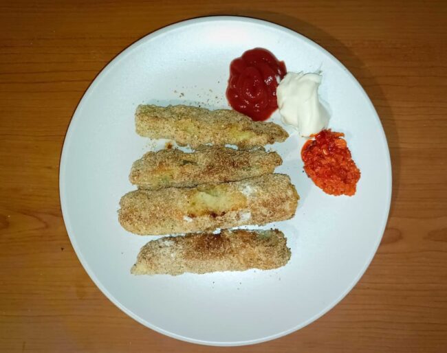 baked zucchini fries on a plate with sauces