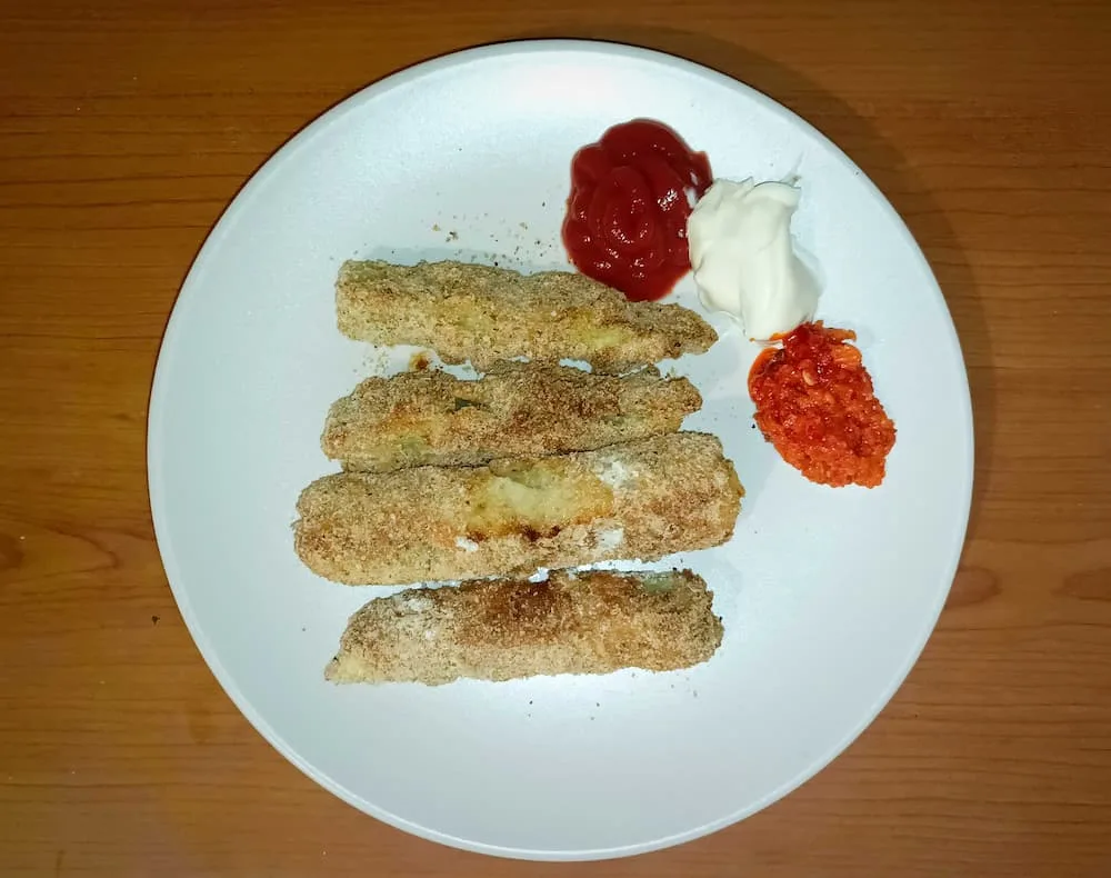 baked zucchini fries on a plate with sauces