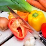 peppers and onions on a working surface with a knife and other vegetables
