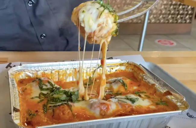 How to Reheat Chicken Parm (The Best Way!)-Mortadella head meatball parmesan dish with parmesan cheese, marinara sauce, basil, and mozzarella pizza cheese.
