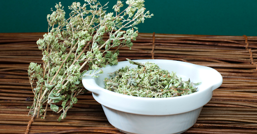 Fresh oregano and thyme leaves side by side
