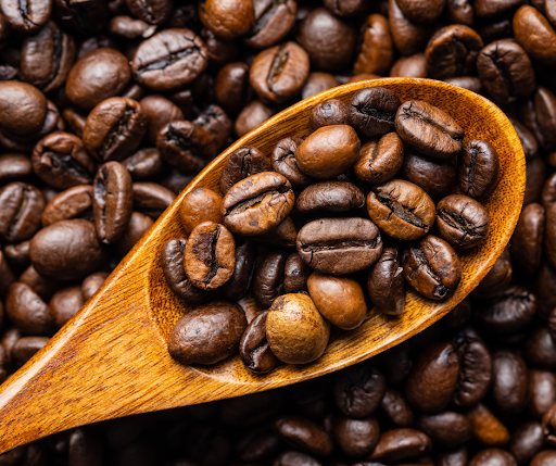 a mix of arabica and robusta beans on a wooden spoon, with other beans in the background.