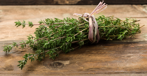 Thyme sprigs with small green leaves on cutting board