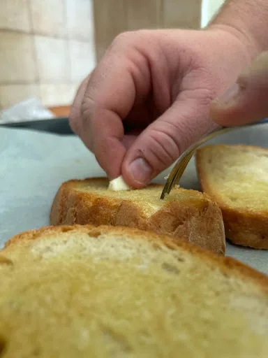 brushing a garlic clove on a fresh homemade bruschetta 