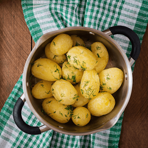 Whole potatoes being placed into pot of water